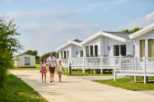 A man and two children walking down a path in front of a white trailer.