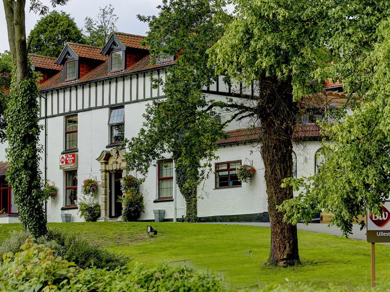 Hotel Exterior seen through the trees infront of the property