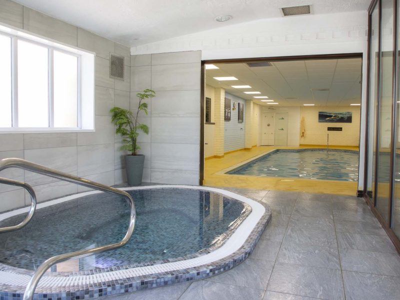 Hot Tub with stepped access and handrails a swimming pool can be seen in the background