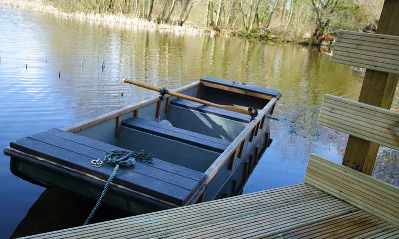 Wooden boat moored at tranquil forest lake.