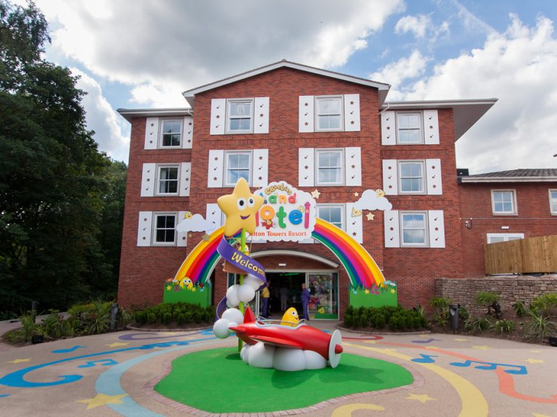 the exterior of the cbeebies hotel with a rainbow and logo over the entrance door