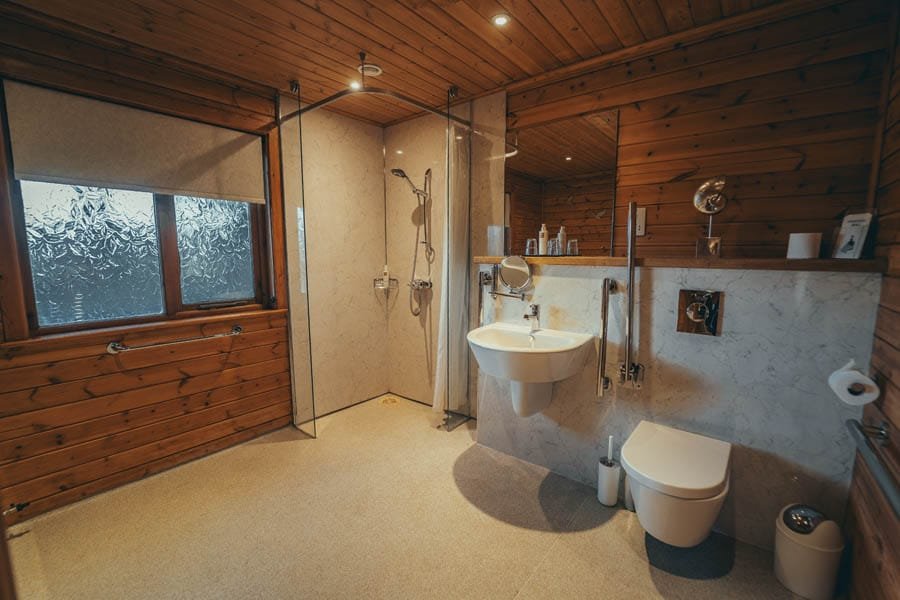 Modern bathroom with wooden accents and glass shower.