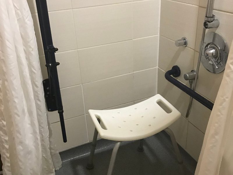 a wet room shower with shower stool and handrails present