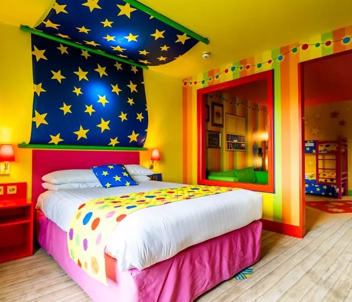 a bright colour room with double bed in the forground and a bunk bed in the background