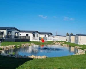 Pond at residential park with modern mobile homes and fountain.