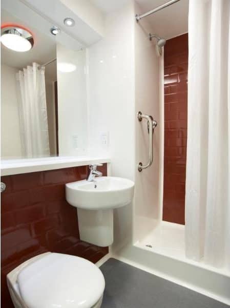 Modern bathroom with red tiles and white fixtures.