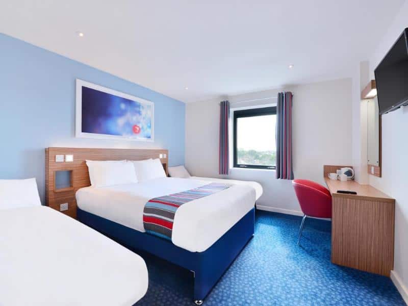 Bright modern hotel room with double bed and workspace.