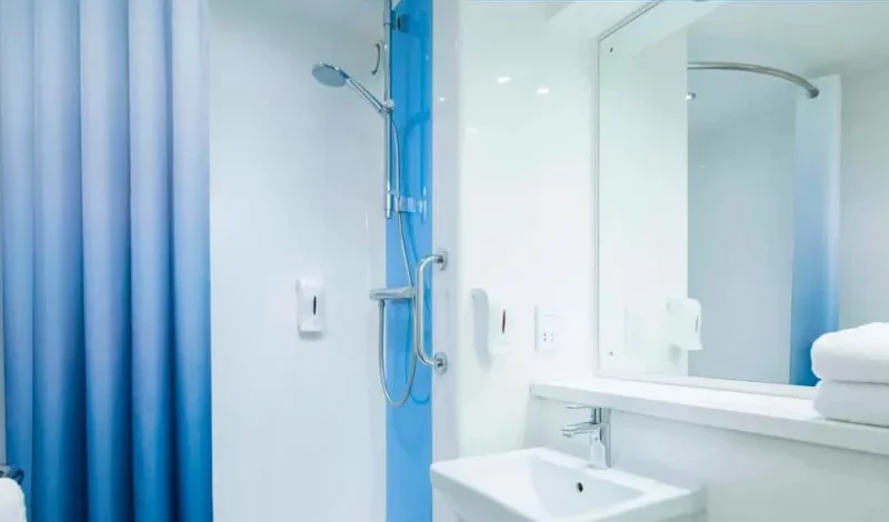 Modern bathroom with blue shower curtain and white sink.