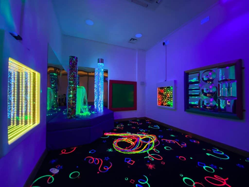Colorful sensory room with glowing lights and interactive displays.
