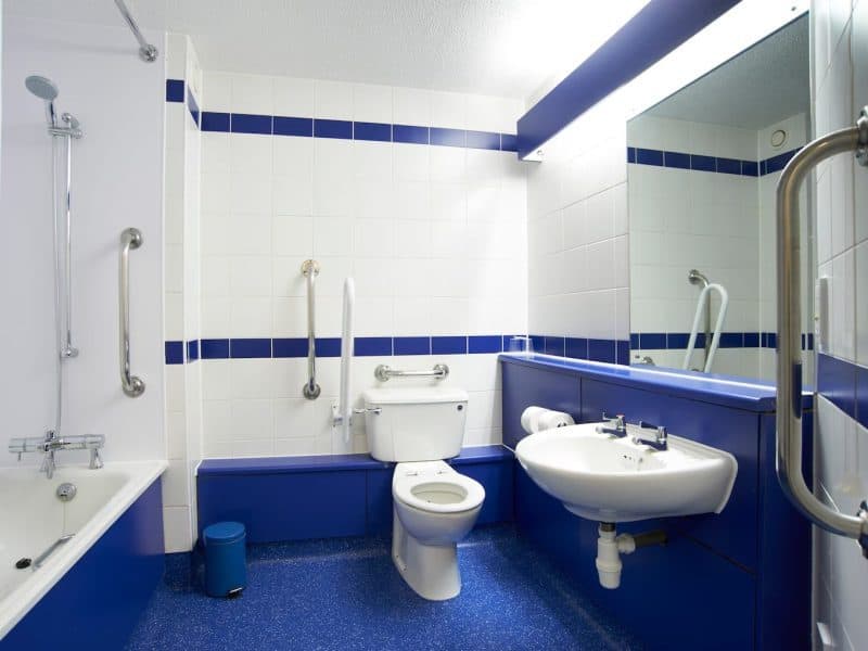 Accessible bathroom with safety handles and blue accents.