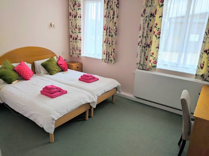 Bright twin bedroom with pink accents and floral curtains.