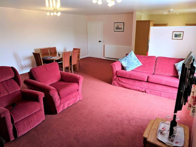 Spacious living room with pink furniture and carpet.