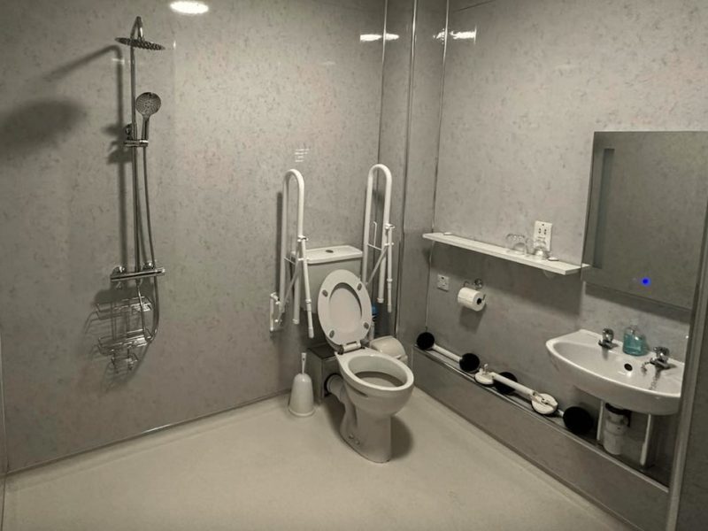 Accessible bathroom with safety handrails and shower.