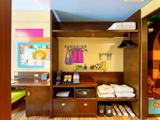 Colorful hotel room with organized closet and desk area.