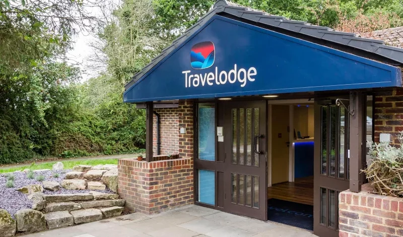 Travelodge hotel entrance with logo and garden.