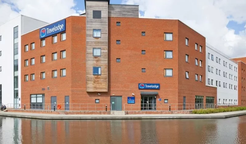 Travelodge hotel exterior by canal on cloudy day.