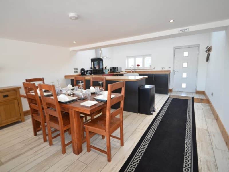 Modern kitchen with dining area, wooden furniture, and sleek design.