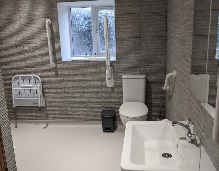 Modern accessible bathroom with textured tiles and natural light.