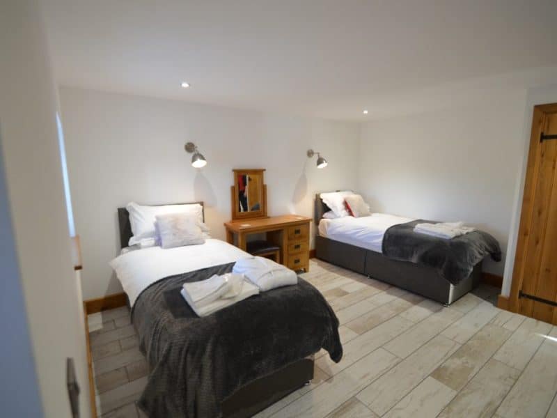 Modern twin bedroom with wooden accents and white walls.