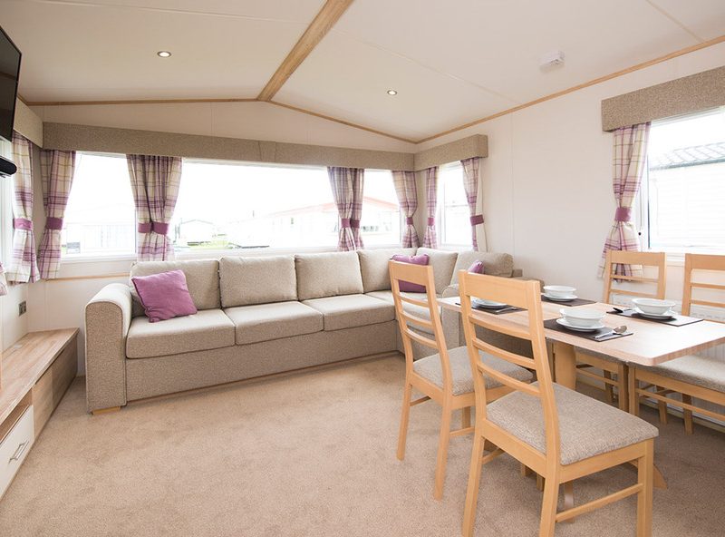 Spacious caravan interior with sofa and dining area.