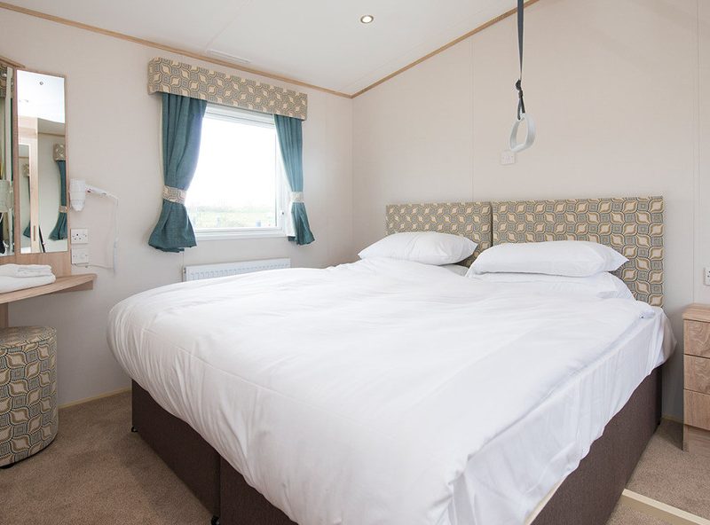 Neatly arranged bedroom with white bedding and teal accents.