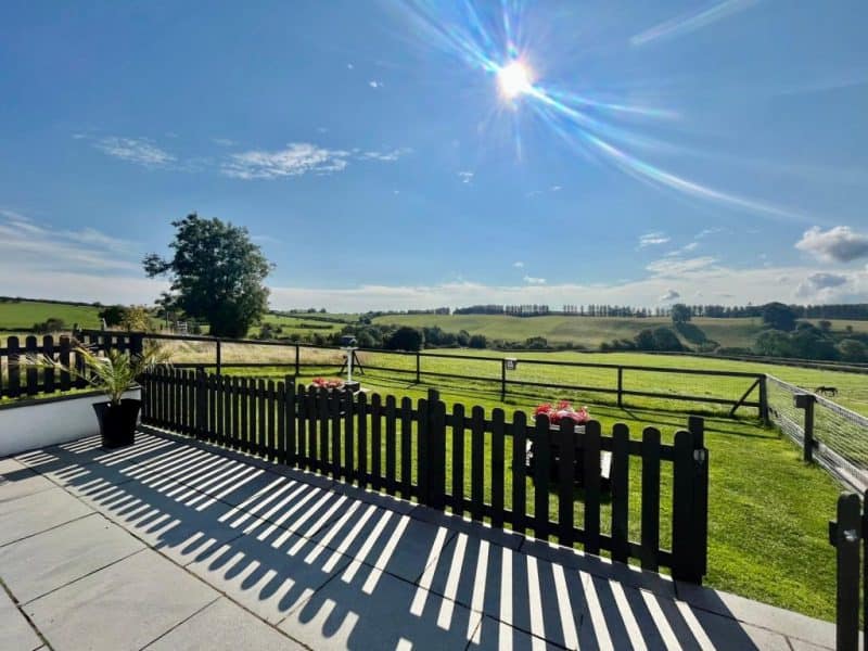 Sunny countryside patio with scenic green hills view.