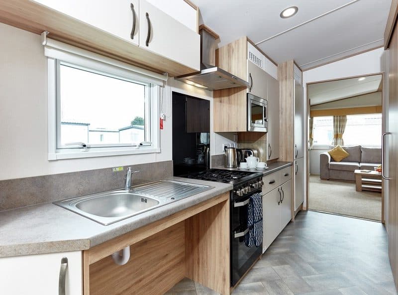 Modern mobile home interior with kitchen and living area.