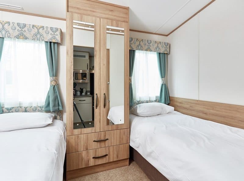 Twin beds in a cozy, bright hotel room.