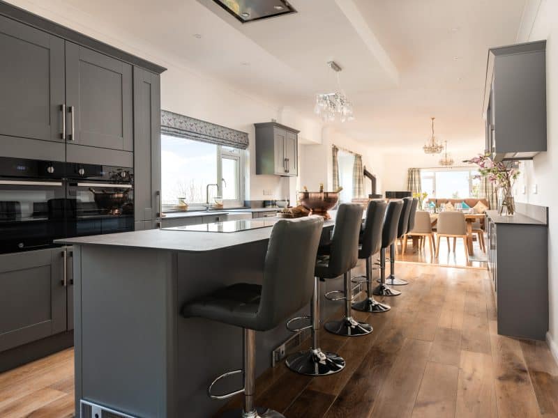 Modern kitchen with bar stools and integrated appliances.