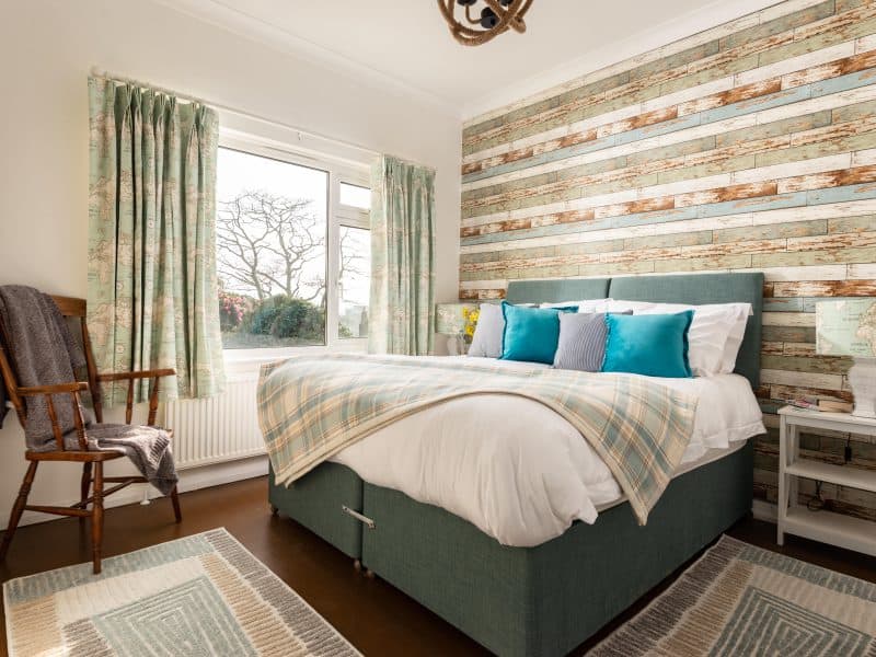 Bright bedroom with rustic wooden wall and garden view.