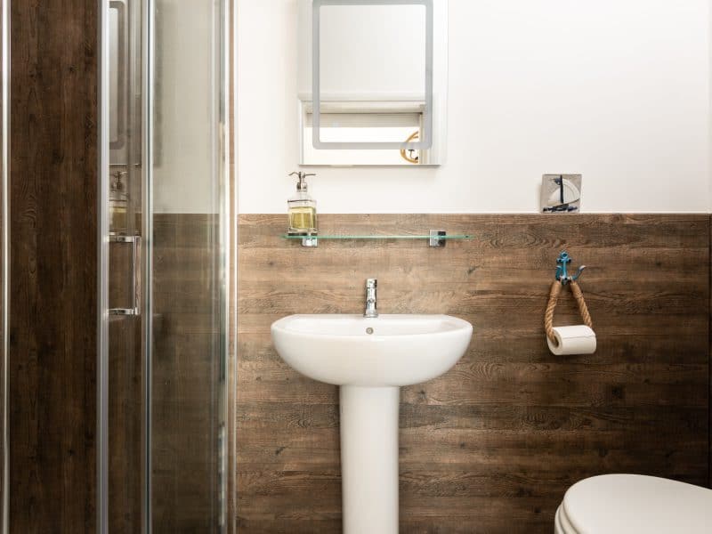 Modern bathroom with glass shower and wooden walls.