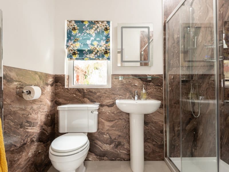 Modern bathroom with marble walls and glass shower.