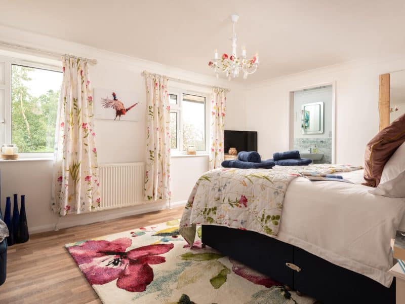 Bright, floral-decorated bedroom with large windows and chandelier.