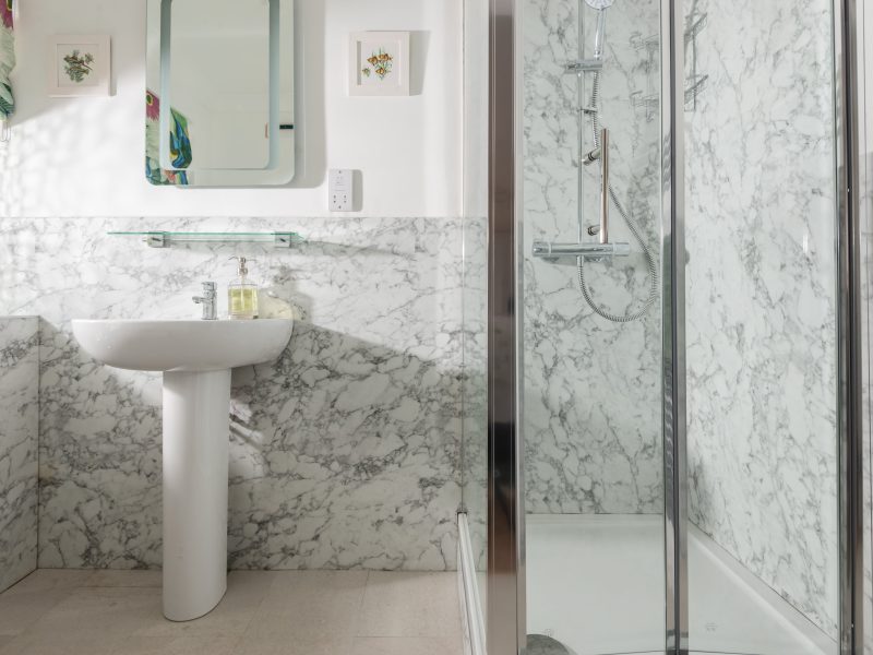 Marble bathroom with sink, mirror, and glass shower.