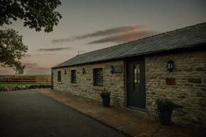 Stone cottage at dusk with outdoor lighting.