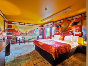 Vibrant Asian-themed bedroom with decorative murals and luxury bedding.