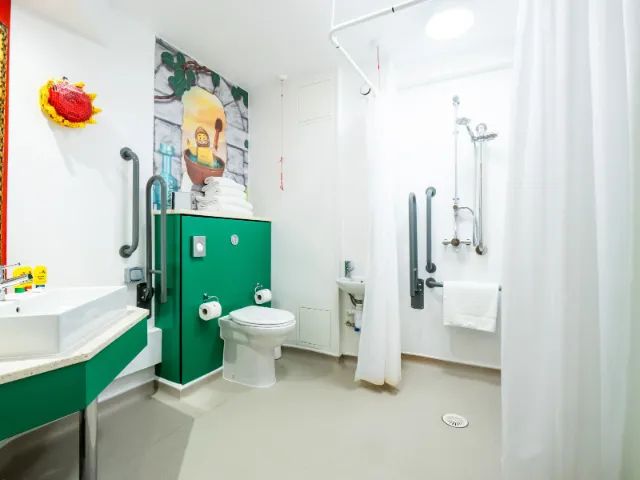 Accessible bathroom with green vanity and grab bars.