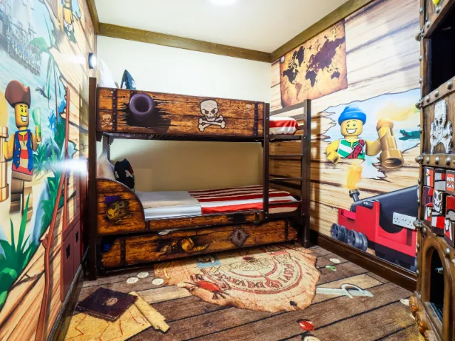 Pirate-themed children's bedroom with bunk beds and LEGO wallpaper.