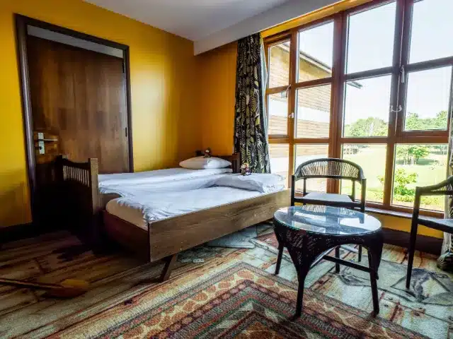 Cozy bedroom with bed, chair, table, and large windows.