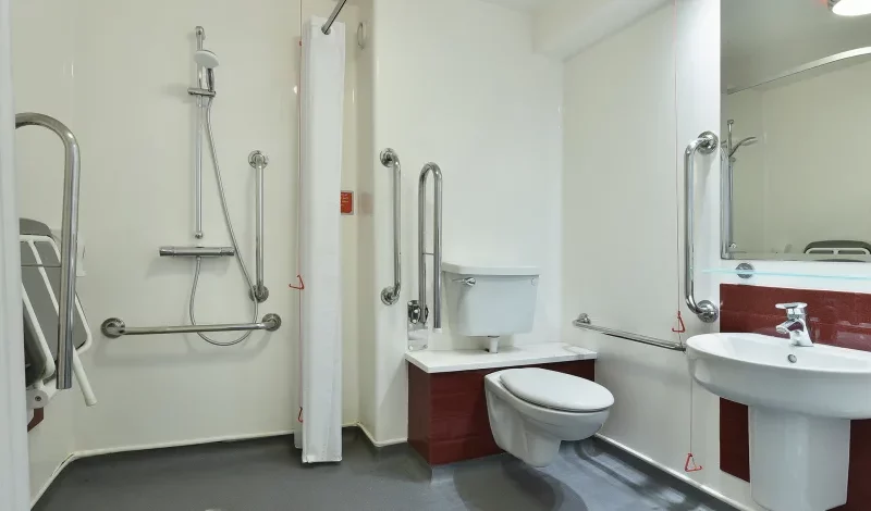 Accessible bathroom with safety grab bars and red accents.