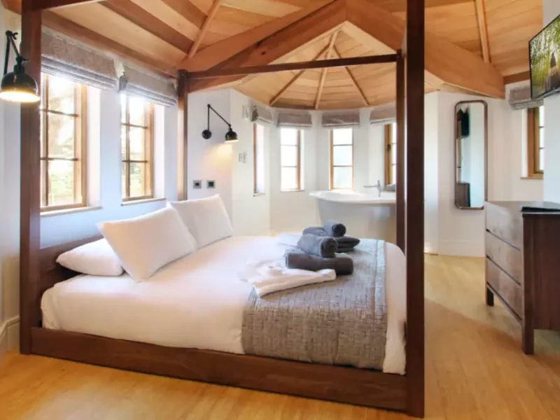 Cozy, modern bedroom with wooden beams and stylish furnishings.