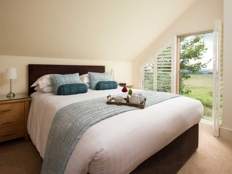 Bright, serene bedroom with scenic countryside view.