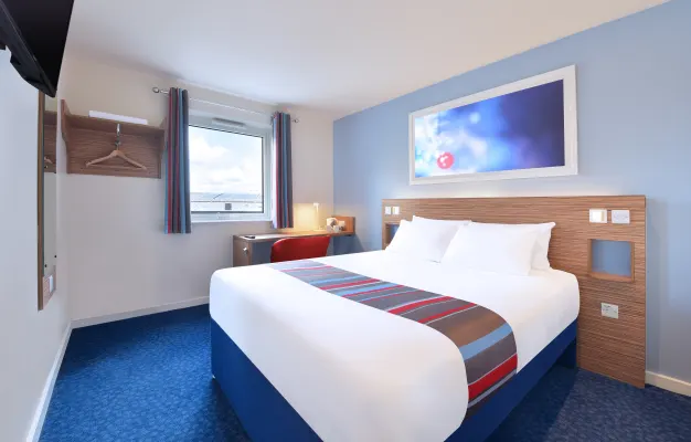 Modern hotel room with blue decor and striped bedspread.