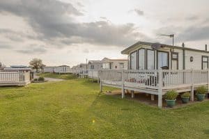 Row of modern caravans in a grassy park.