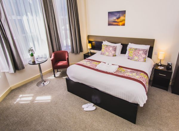 Contemporary hotel room with double bed and stylish decor.