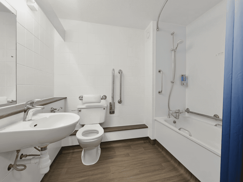 Accessible bathroom interior with grab bars and white tiles.