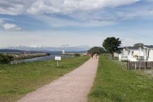 Coastal path by sea with walking people and mobile homes.