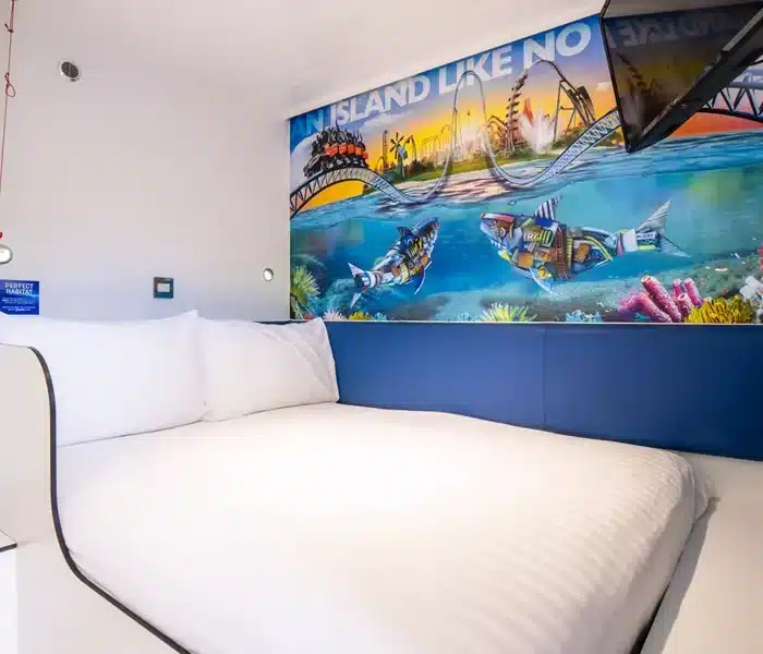 Hotel room with vibrant mural of tropical island scene.