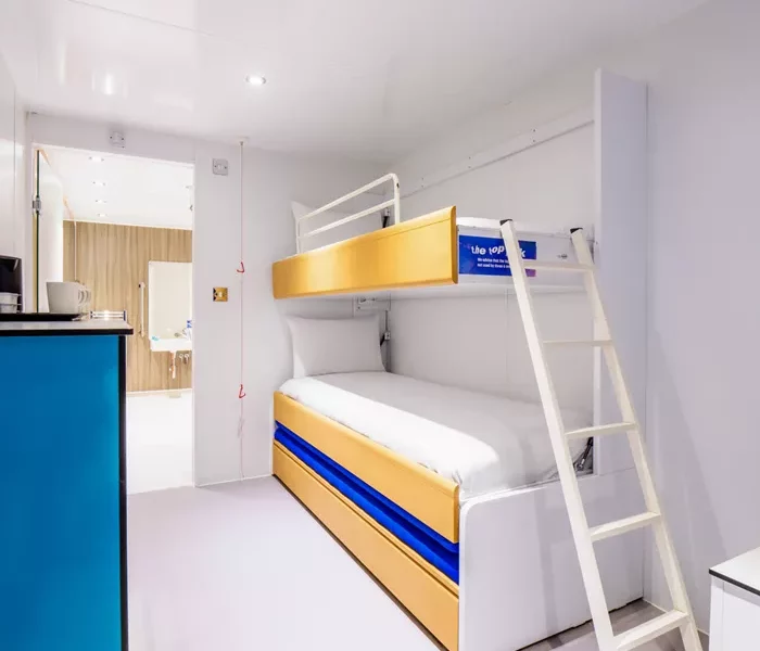 Modern compact ship cabin with bunk beds and kitchenette.