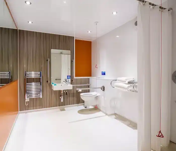 Modern accessible bathroom with orange and wood accents.